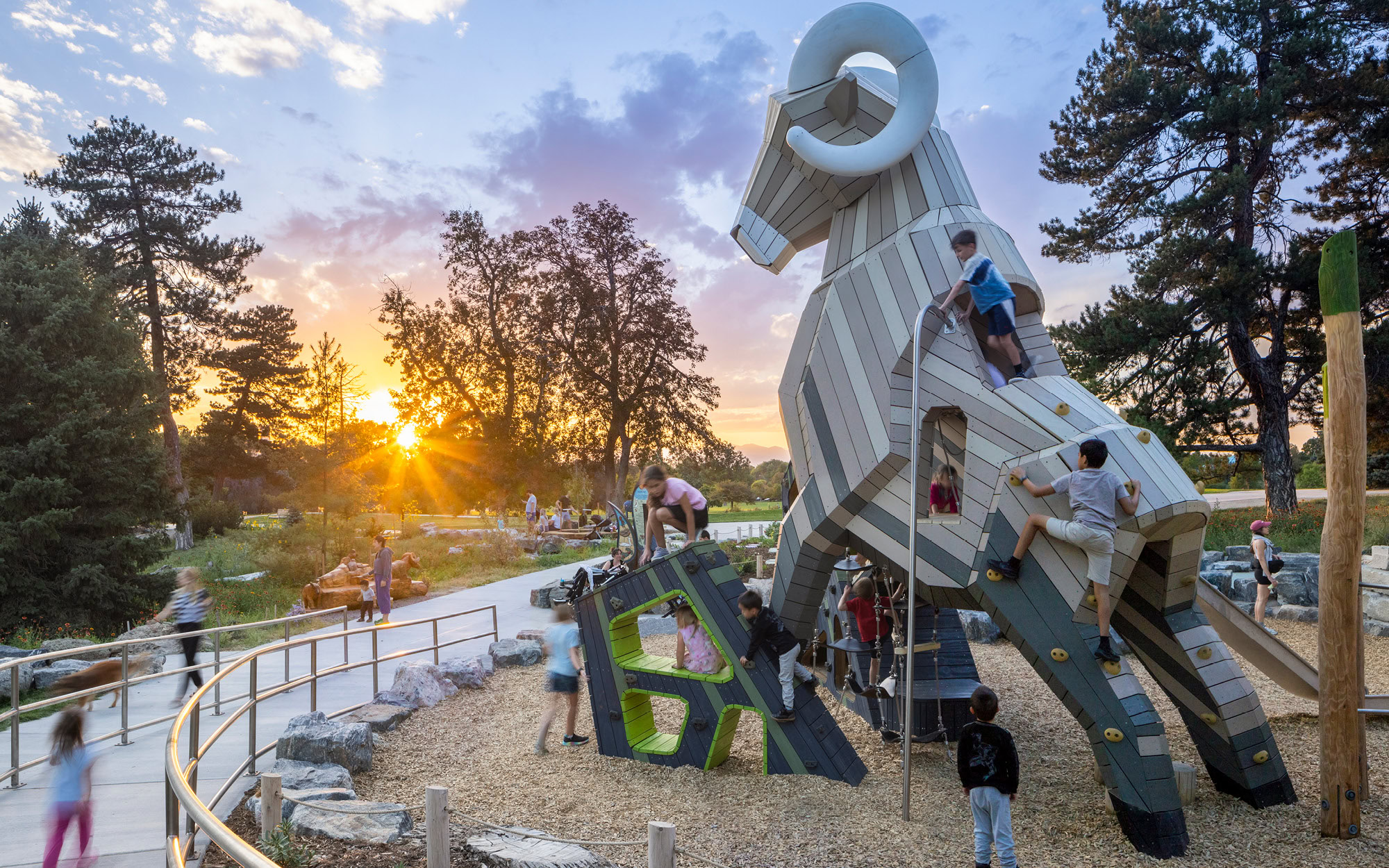 Children climbing a large sculptural playground surrounded by trees